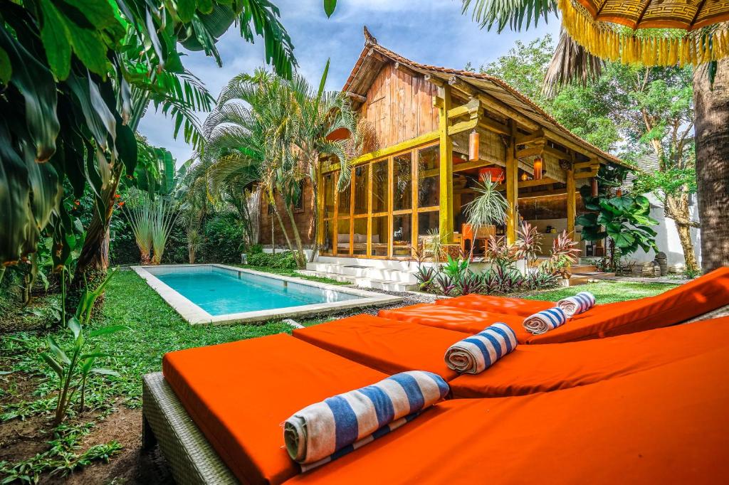 an orange couch in front of a house with a pool at Villa Pagoda, Sumptuous 4BR Villa with Tropical Vibes in Seminyak in Legian