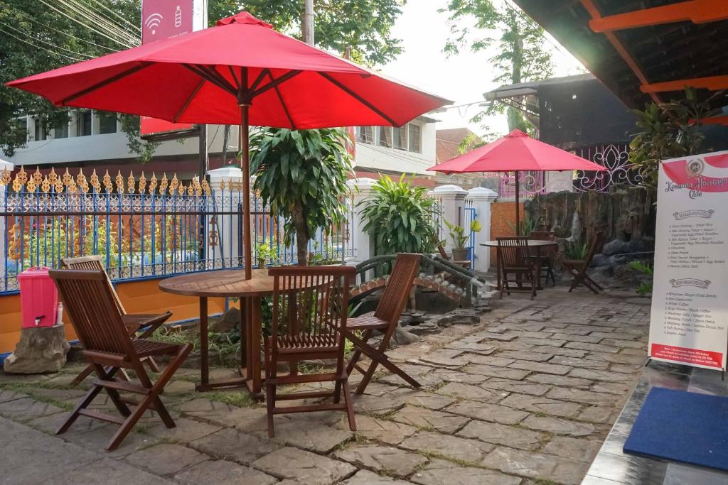 a table and chairs with a red umbrella on a patio at RedDoorz Plus @ Alun Alun Nganjuk in Nganjuk