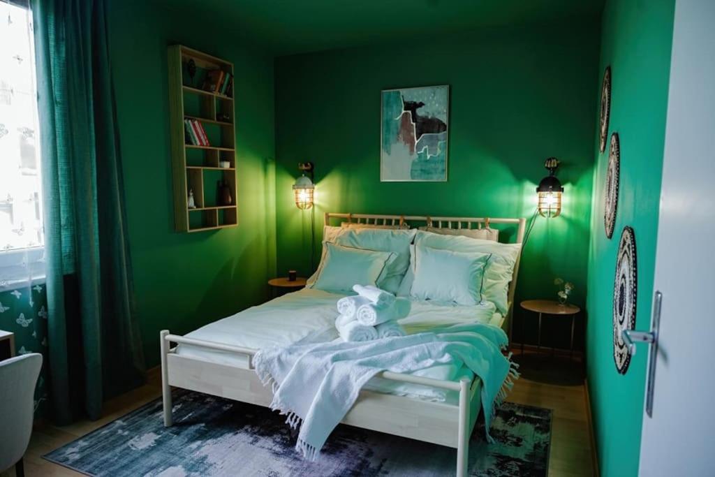 een groene slaapkamer met een wit bed en een groene muur bij Boho-Chic-Wohnung Neusiedl in Neusiedl am See