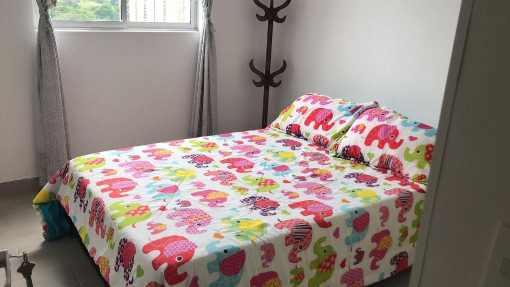 a bed in a room with a flower patterned blanket at Casa Lucy in Ibagué