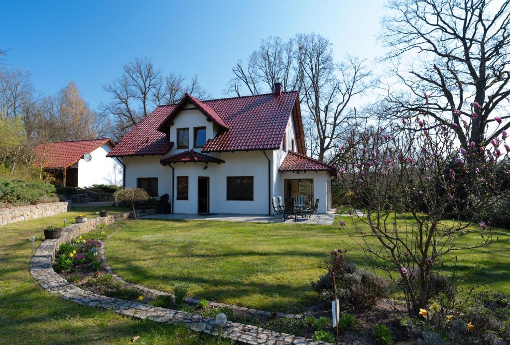 una casa blanca con techo rojo en un patio en DOM POD DĘBAMI, en Gryżyna