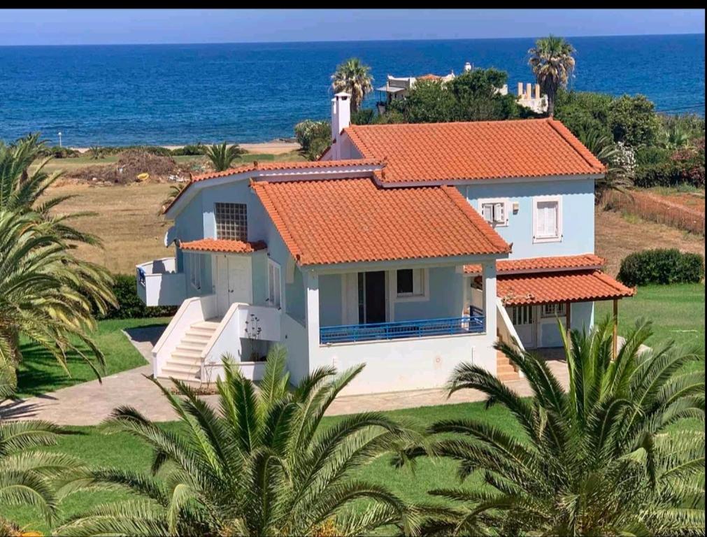 a white house with an orange roof and the ocean at Agrilis Home in Filiatra