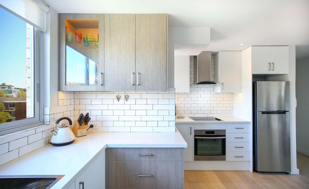 a kitchen with white cabinets and a stainless steel refrigerator at Bondi Aqua Vista - Walk to beach and shops in Sydney