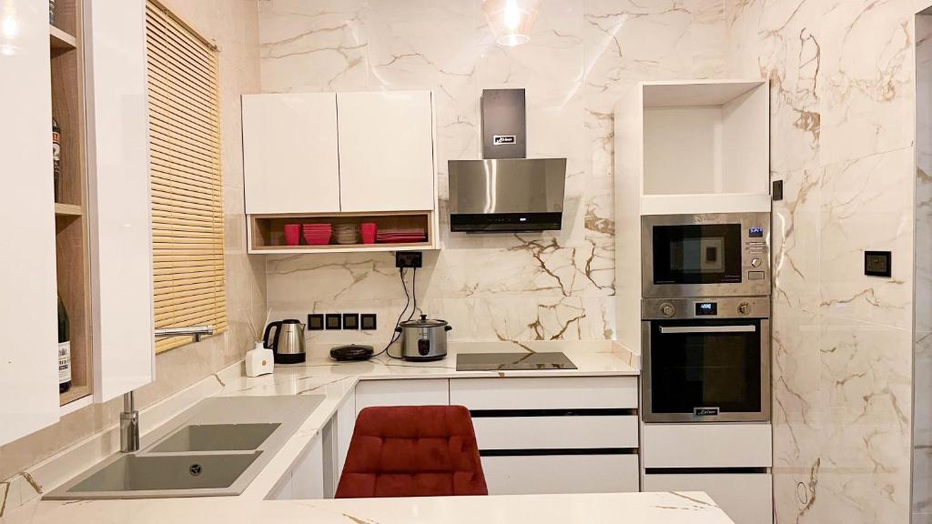 una cocina con armarios blancos y una silla roja. en Mariaddo homes, en Accra