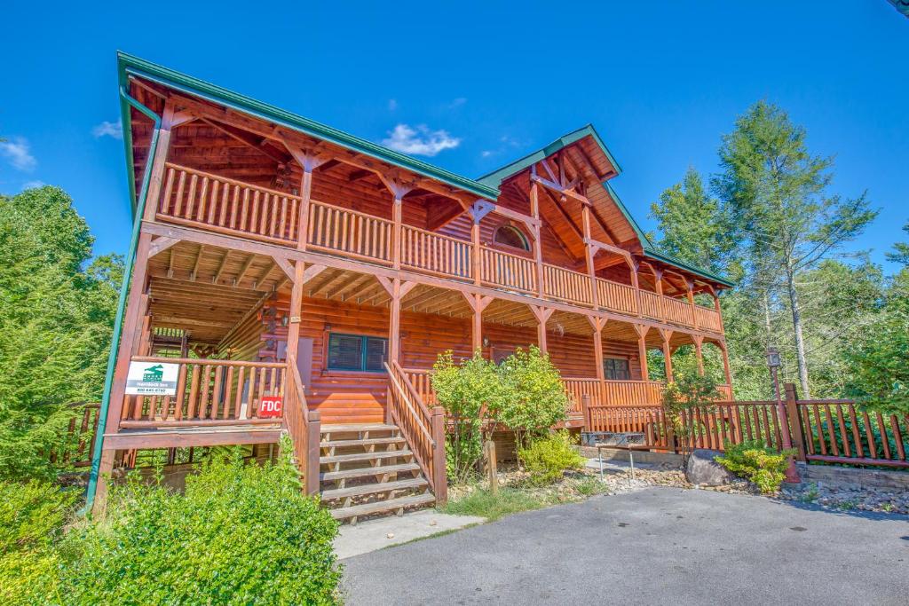 a large log cabin with a staircase to the front of the house at Hemlock Inn, 8 Bedrooms, Theater Room, Pool Table, Hot Tub, Sleeps 38 in Gatlinburg