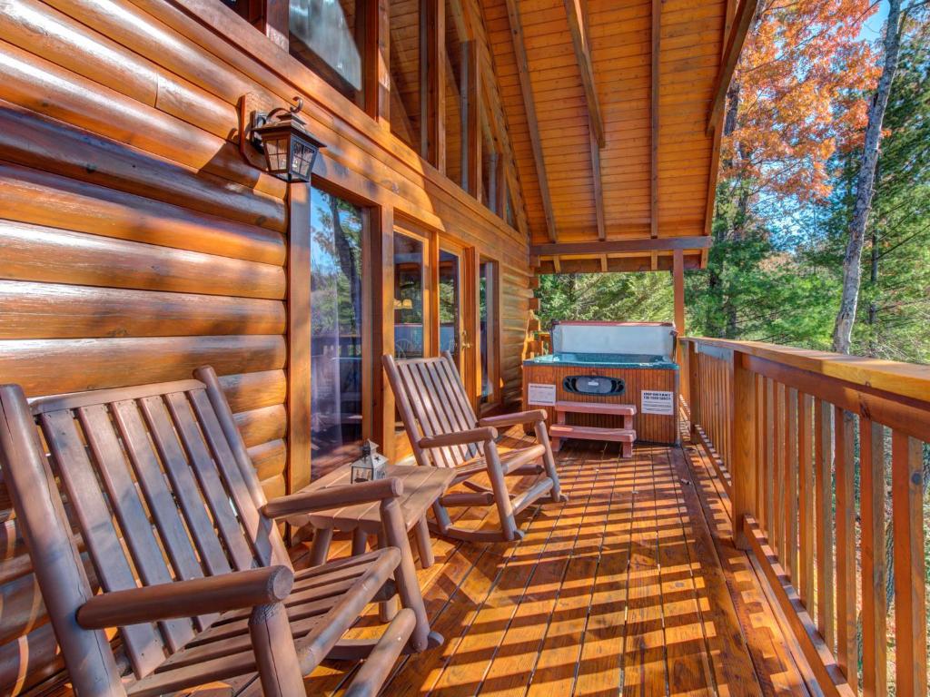a porch of a cabin with two chairs and a grill at Cub’s Corner, 3 Bedrooms, Pool Access, Hot Tub, Pool Table, Sleeps 10 in Gatlinburg