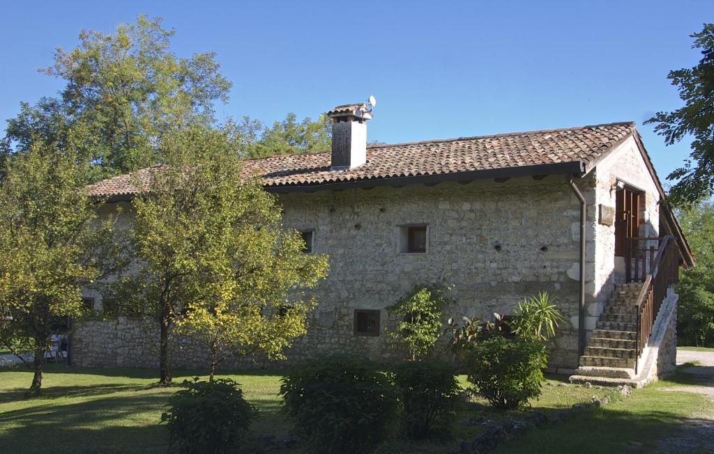 PolcenigoにあるAlbergo Rurale Parco di San Florianoの煙突と木々のある古い石造りの家