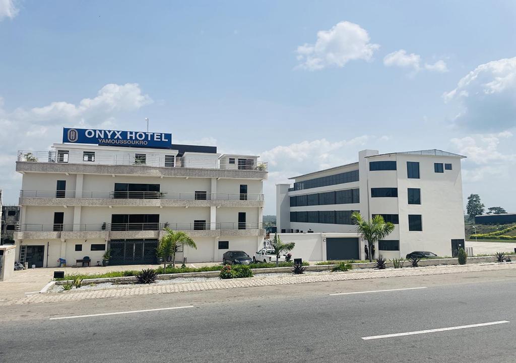 a building with a sign on it next to a road at ONYX HOTEL Yamoussoukro in Yamussukro