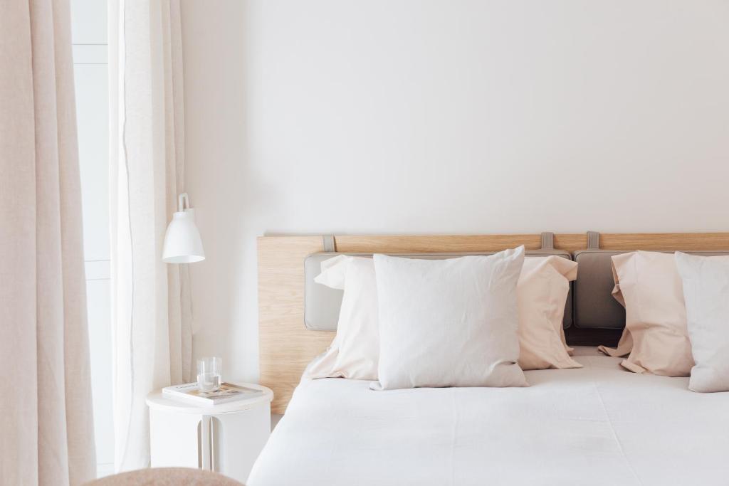 a white bedroom with a bed with white pillows at Plácido y Grata in Seville