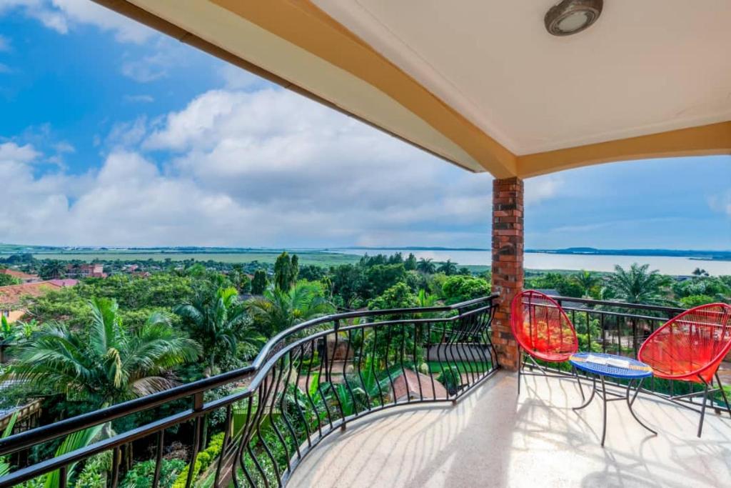 Un balcón con sillas rojas y vistas al océano. en Victoria Breeze Suites, Entebbe en Entebbe