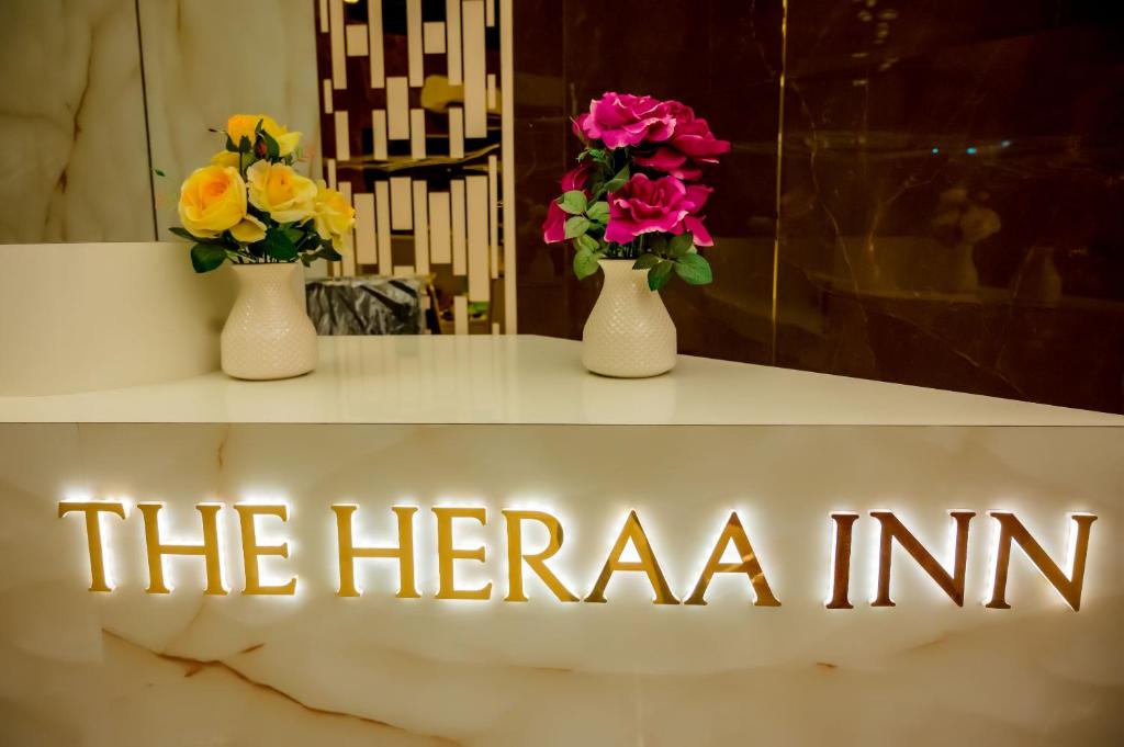 two vases with flowers on a table with the hernia sign at Hotel Heraa International in Mangalore