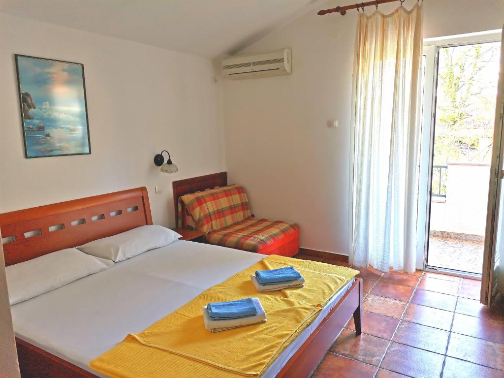 a bedroom with a bed with a yellow blanket and a chair at Apartments Maris in Petrovac na Moru