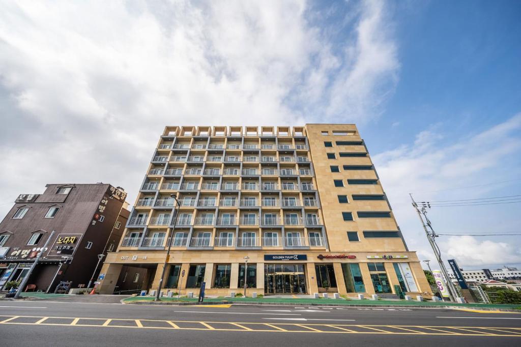 a large building on the corner of a street at SH Golden Tulip Seongsan Stay in Seogwipo