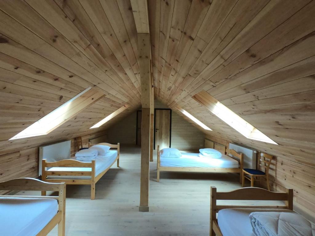 a large wooden room with three beds in it at Cosy chalet in nature in Bastogne