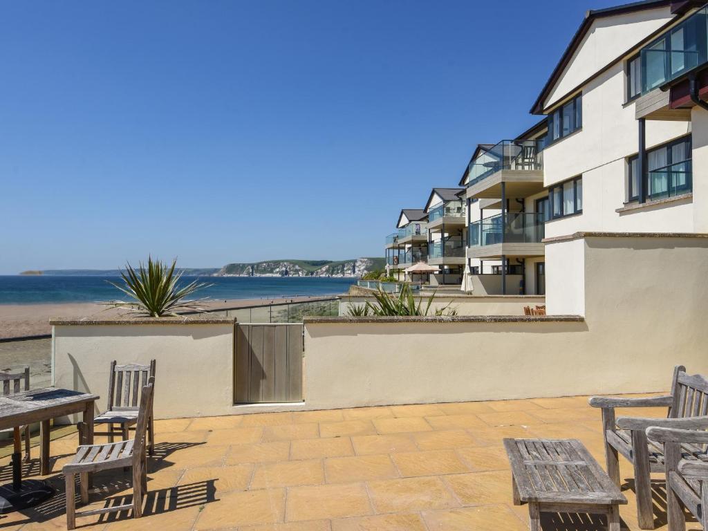 un patio avec des tables et des chaises à côté d'un bâtiment dans l'établissement 13 Burgh Island Causeway, à Bigbury on Sea