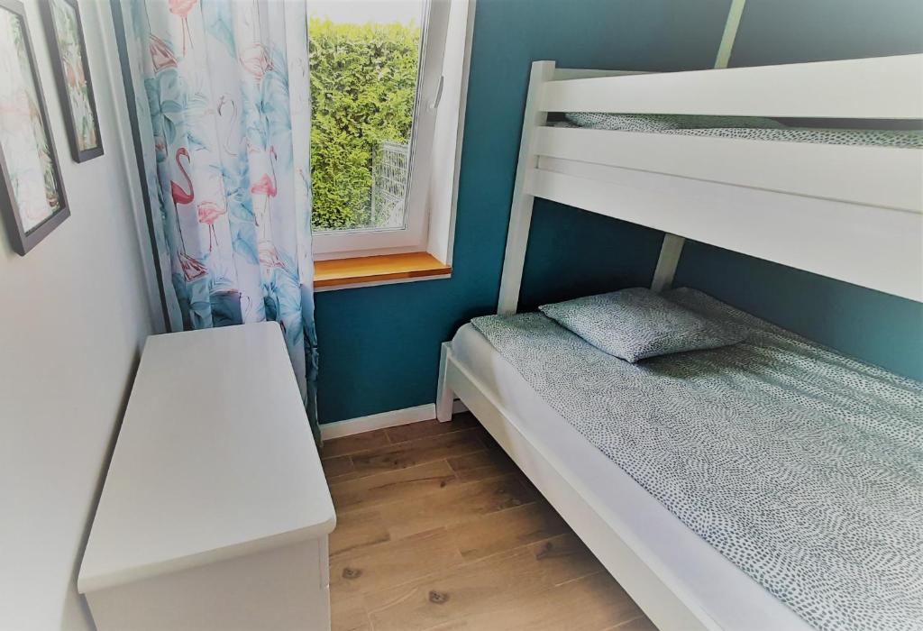 a small bedroom with a bunk bed and a window at Domki Flaming in Dąbki