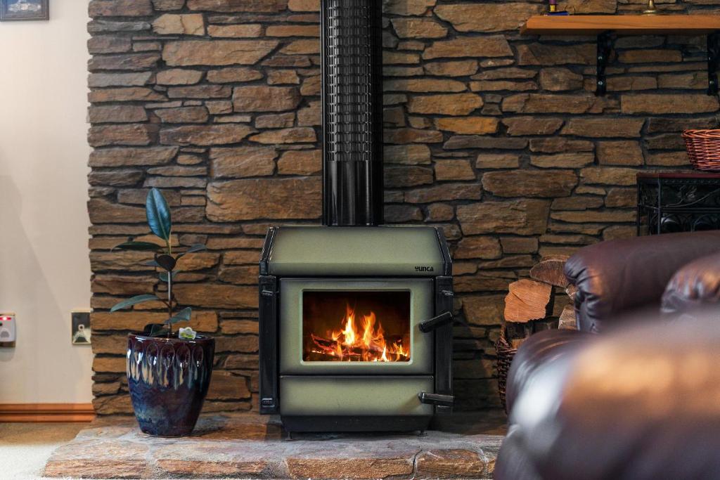 a fireplace in a living room with a stone wall at Charming house with lovely views in Queenstown