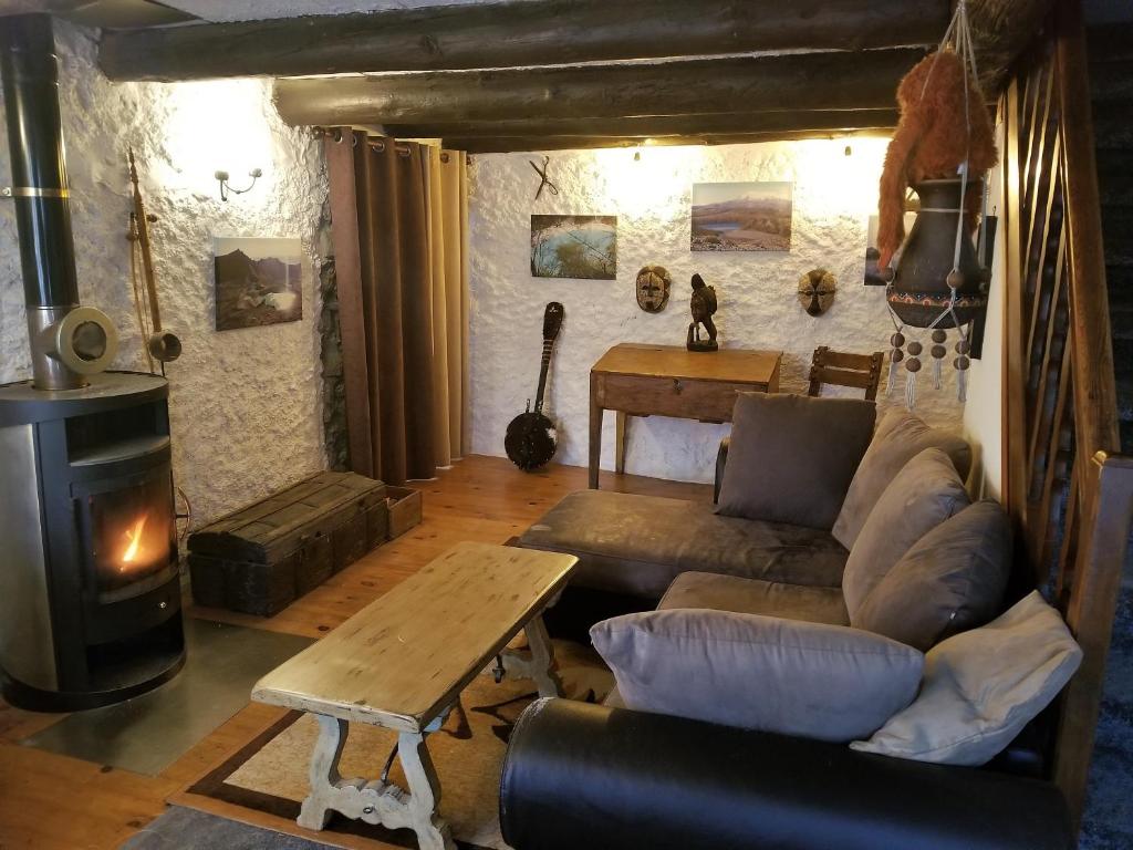sala de estar con sofá y estufa de leña en Haut de grange en pierre, en Roquebillière