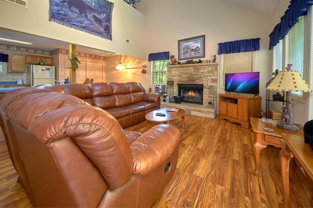 a living room with a leather couch and a fireplace at Mountain Hideaway, 1 Bedroom, Sleeps 2, Wood Fireplace, WiFi, Pool Table in Gatlinburg