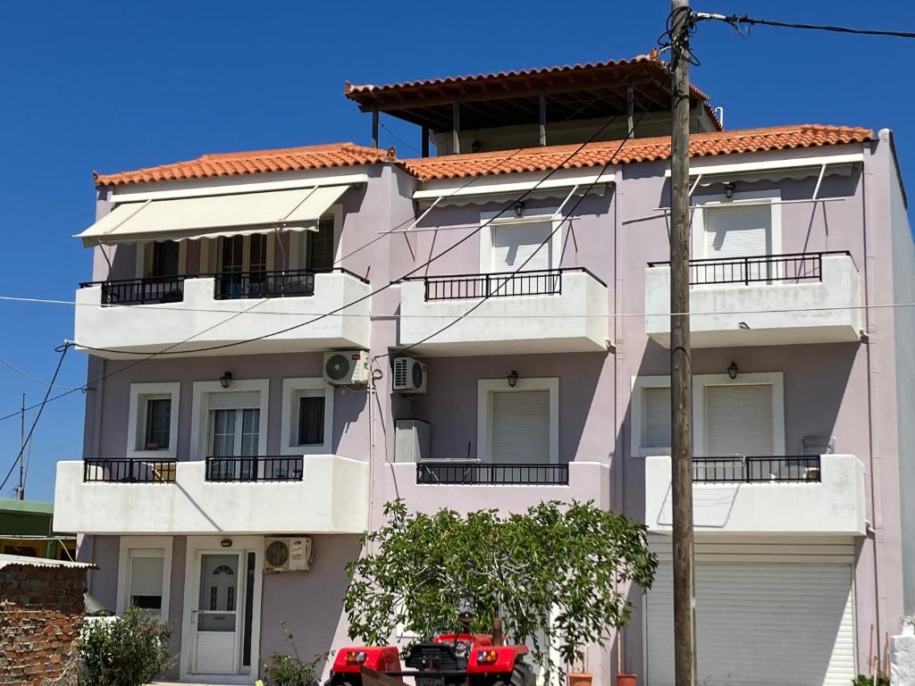 różowy budynek z czerwonym dachem w obiekcie VOULA'S HOUSES w mieście Neo Karlowasi
