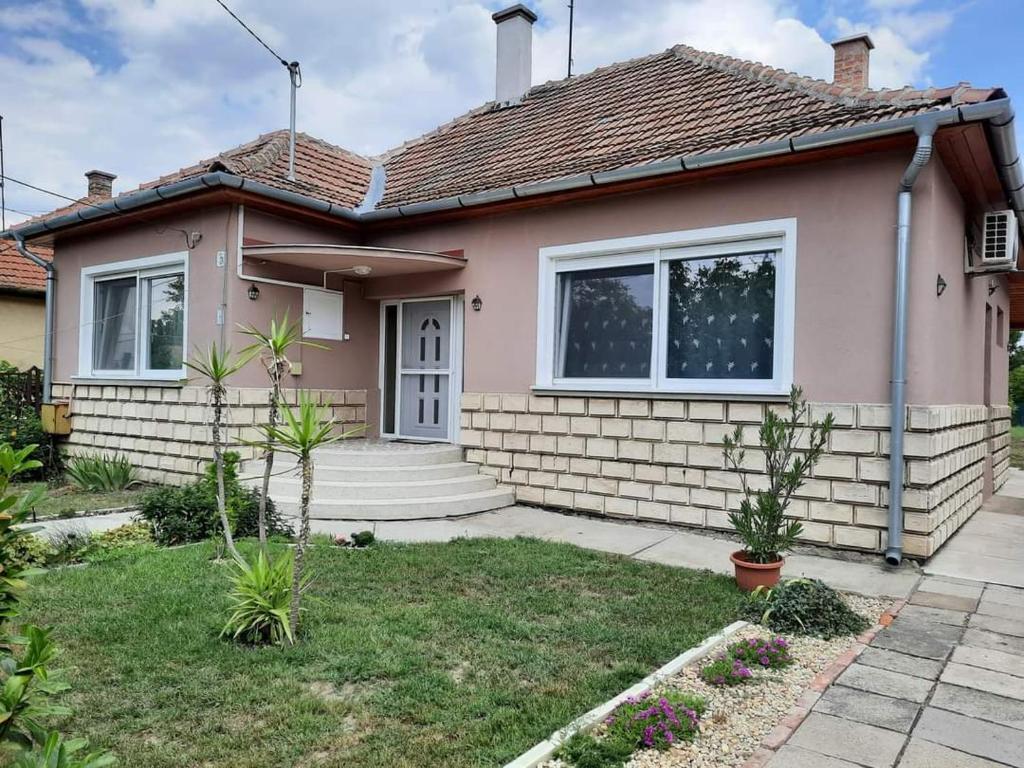 une maison rose avec une terrasse couverte dans l'établissement Alexander apartman, à Gyula