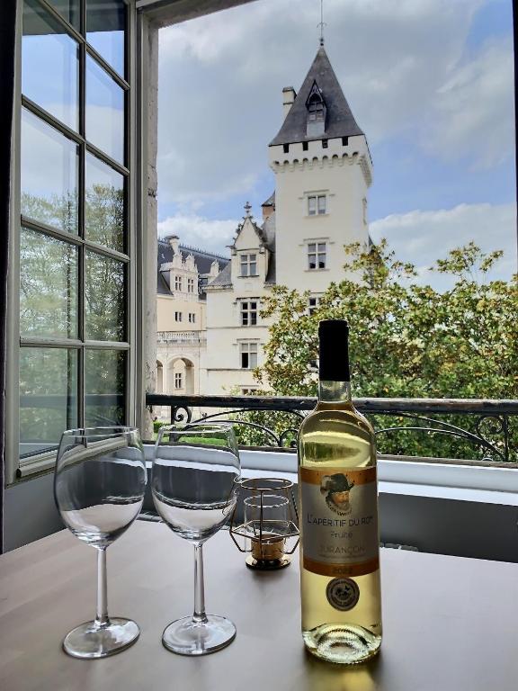 une bouteille de vin et deux verres sur une table avec un château dans l'établissement Vue magique sur le château dans un quartier populaire, à Pau
