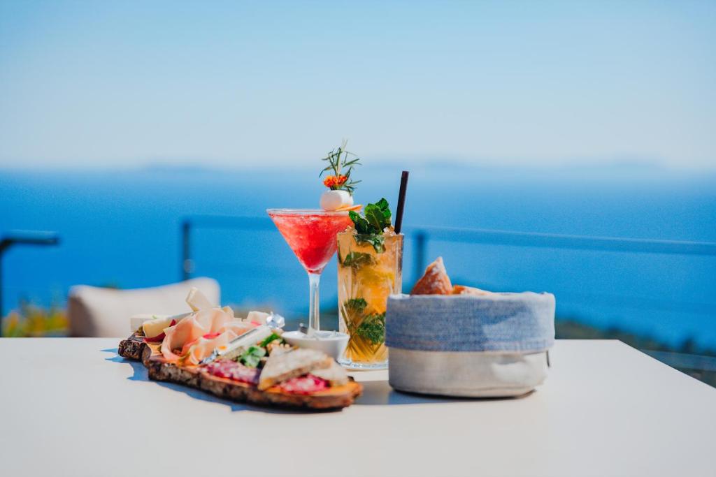 a table topped with a sandwich and a drink at Hôtel La Villa Douce in Rayol-Canadel-sur-Mer
