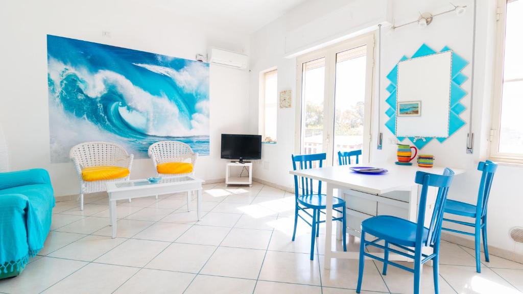 un comedor con sillas azules y una mesa blanca en Welcomely - Casa Dei Catalani, en Torre Grande