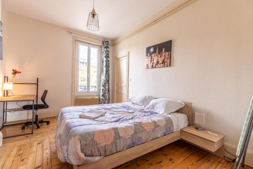 a bedroom with a bed and a desk in it at F3 Av république avec garage (c) in Clermont-Ferrand