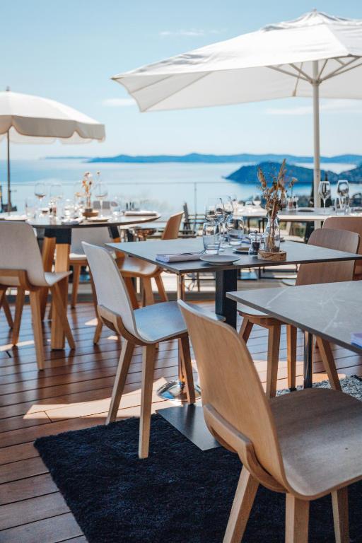 a restaurant with tables and chairs and umbrellas at Hôtel La Villa Douce in Rayol-Canadel-sur-Mer