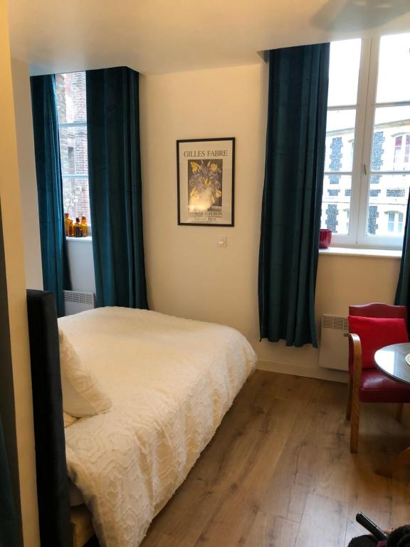 une chambre avec un lit avec des rideaux bleus et une chaise dans l'établissement Le studio d'Eva, à Honfleur