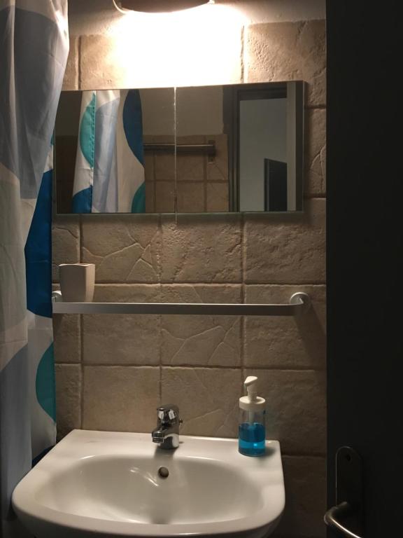a bathroom sink with a mirror and a bottle of soap at Cristi Rooms in Livadi