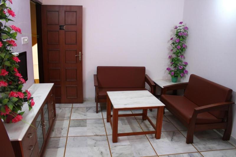 a waiting room with chairs and tables and flowers at Shreeji Service Apartment in Vadodara