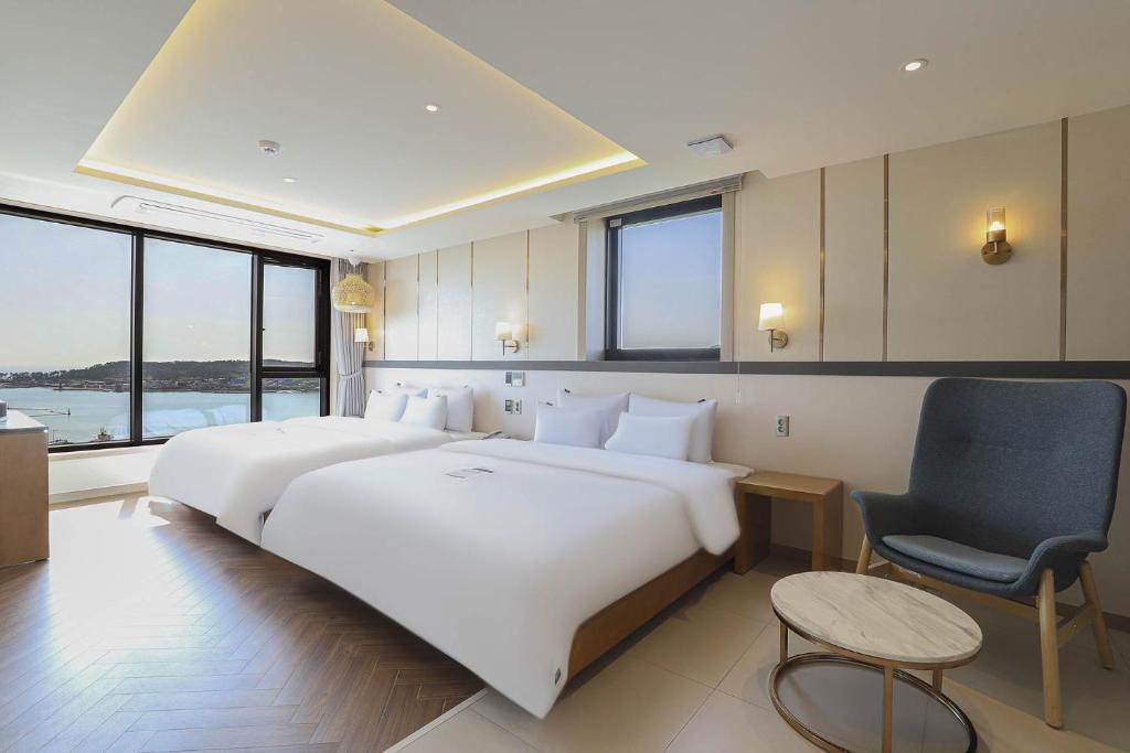 a bedroom with a large white bed and a chair at H avenue Kijang Ilgwang in Busan
