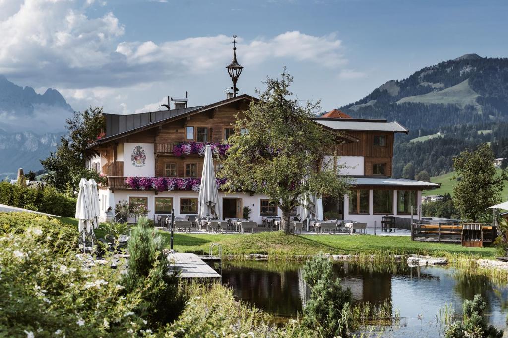 a hotel with a lake in front of a building at Hotel Chalets Grosslehen in Fieberbrunn