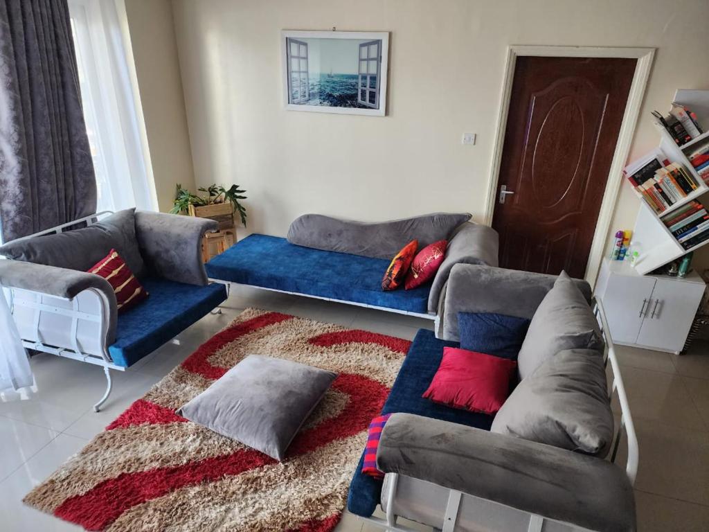 uma sala de estar com um sofá azul e um tapete em Kings Millennium Apartments- 3Bdrm Aprt, All Ensuite, 7km to JKI Airport, 7km to CBD em Nairobi