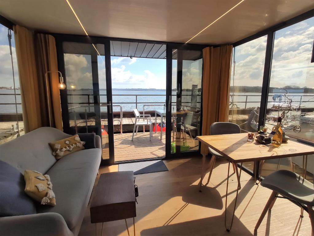 a living room with a table and chairs and a balcony at Hausboot Hilja - neuer Ankerplatz! in Schleswig