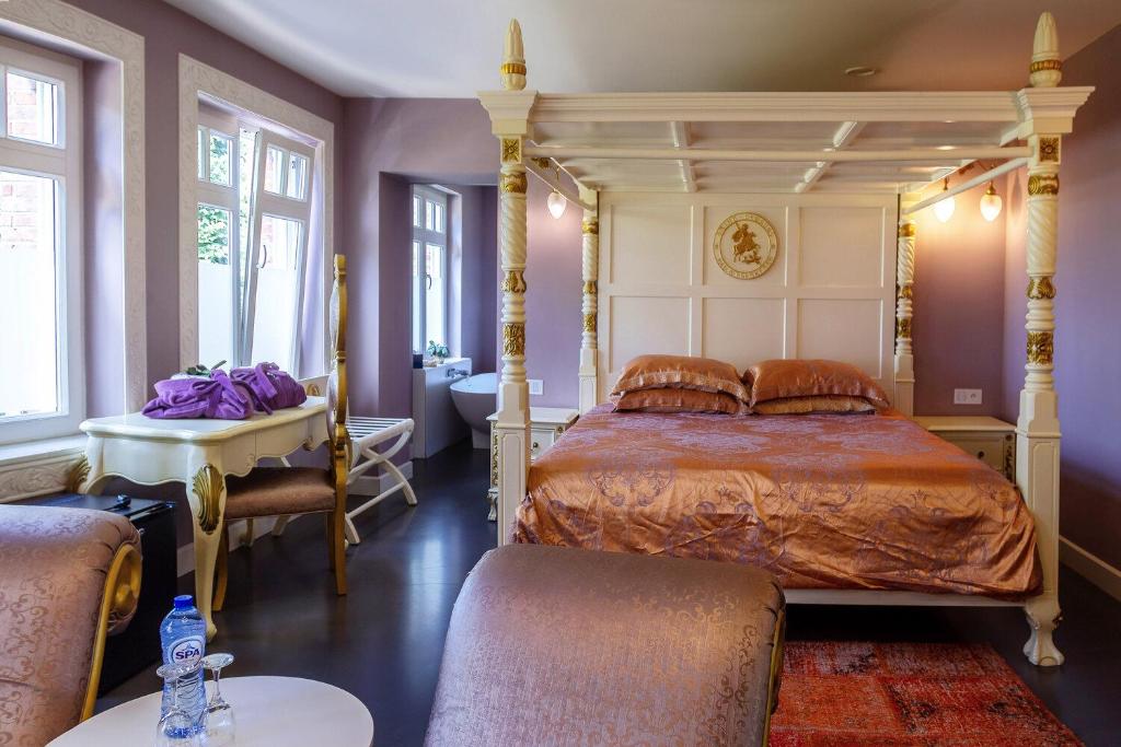 a bedroom with a canopy bed and a bathroom at Bruges Luxury Suites in Bruges