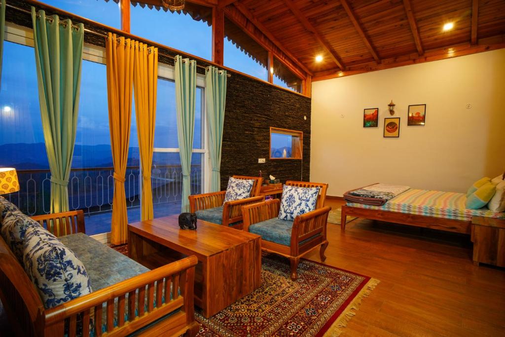 a living room with furniture and a large window at Shivoham Himalayan Resort in Almora