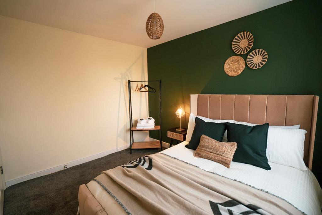 ein Schlafzimmer mit einem Bett mit einer grünen Wand in der Unterkunft Kandaka-Specious Stylish Home - Suitable for Contractors in Killingbeck