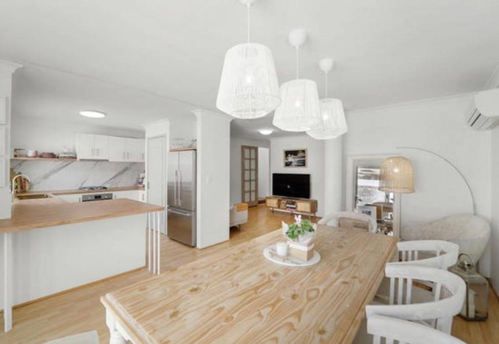 a kitchen and living room with a wooden table and chairs at The “Pretty Beach House” in Perth