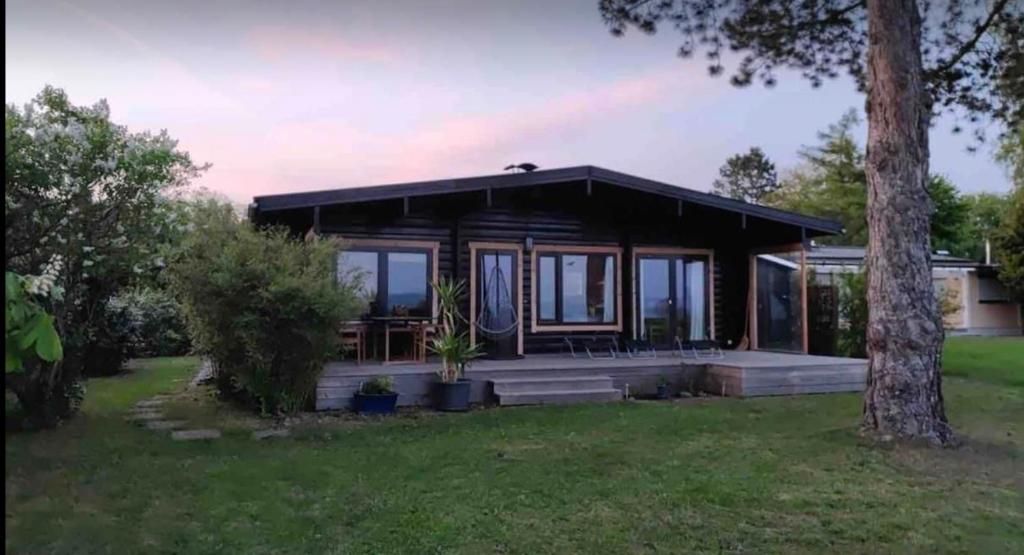 uma pequena casa com um alpendre e uma árvore em Chalet am Feldrand em Starzach