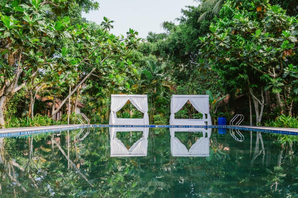 a pool at the resort with trees in the background at An Nhien Retreat Phu Quoc with Yoga Daily & Beach access in Phu Quoc