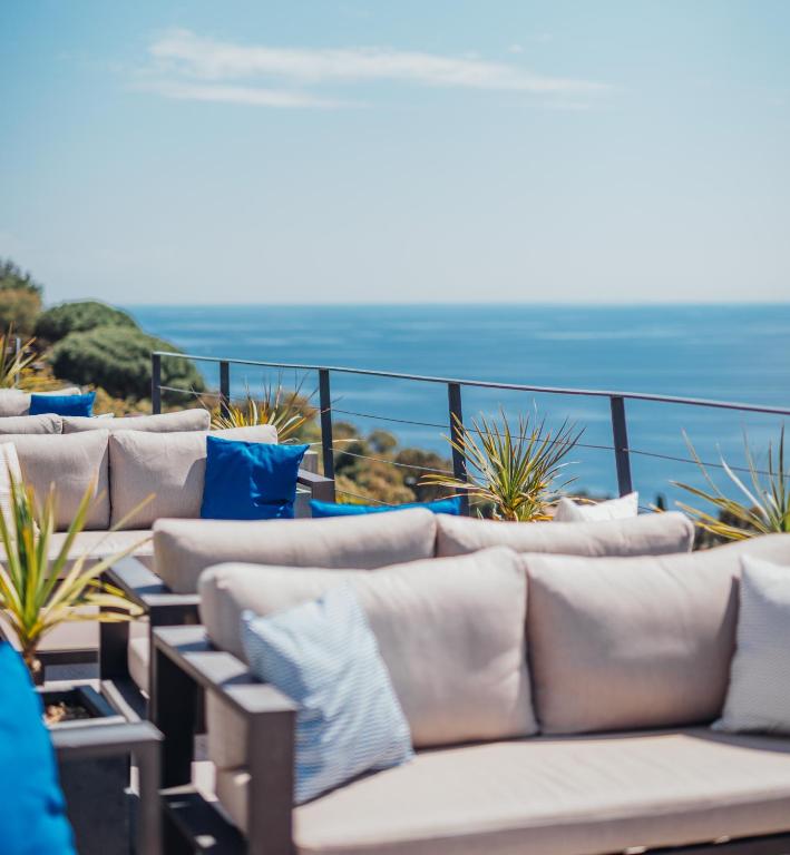 a row of couches on a balcony with the ocean at Hôtel La Villa Douce in Rayol-Canadel-sur-Mer