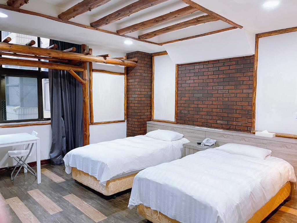 a bedroom with two beds and a brick wall at A22 Wei Lu Hotel in Zhongli