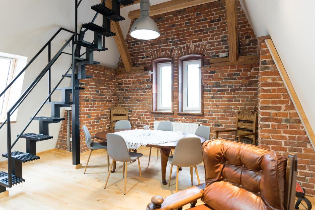 comedor con pared de ladrillo, mesa y sillas en Apartament w stylu Loft, en Spała