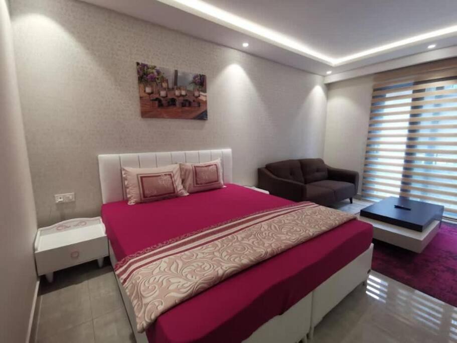 een slaapkamer met een groot bed en een bank bij Intimate Studio Apartment - Mirage Residence in Accra