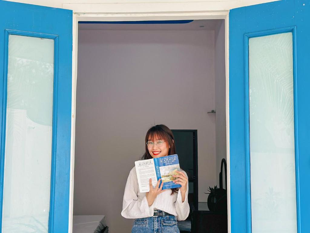 a woman standing in a doorway holding a book at Ben's House 2 in Quy Thượng