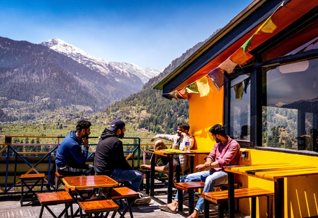 a group of people sitting at tables on a balcony at La Vaca India Manali in Manāli