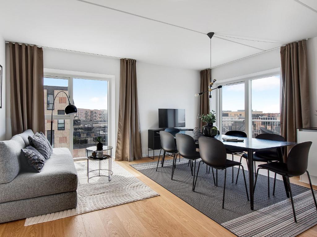 a living room with a table and chairs and a dining room at Sanders Arena - Chic Three-Bedroom Apartment Close to Metro Station in Copenhagen